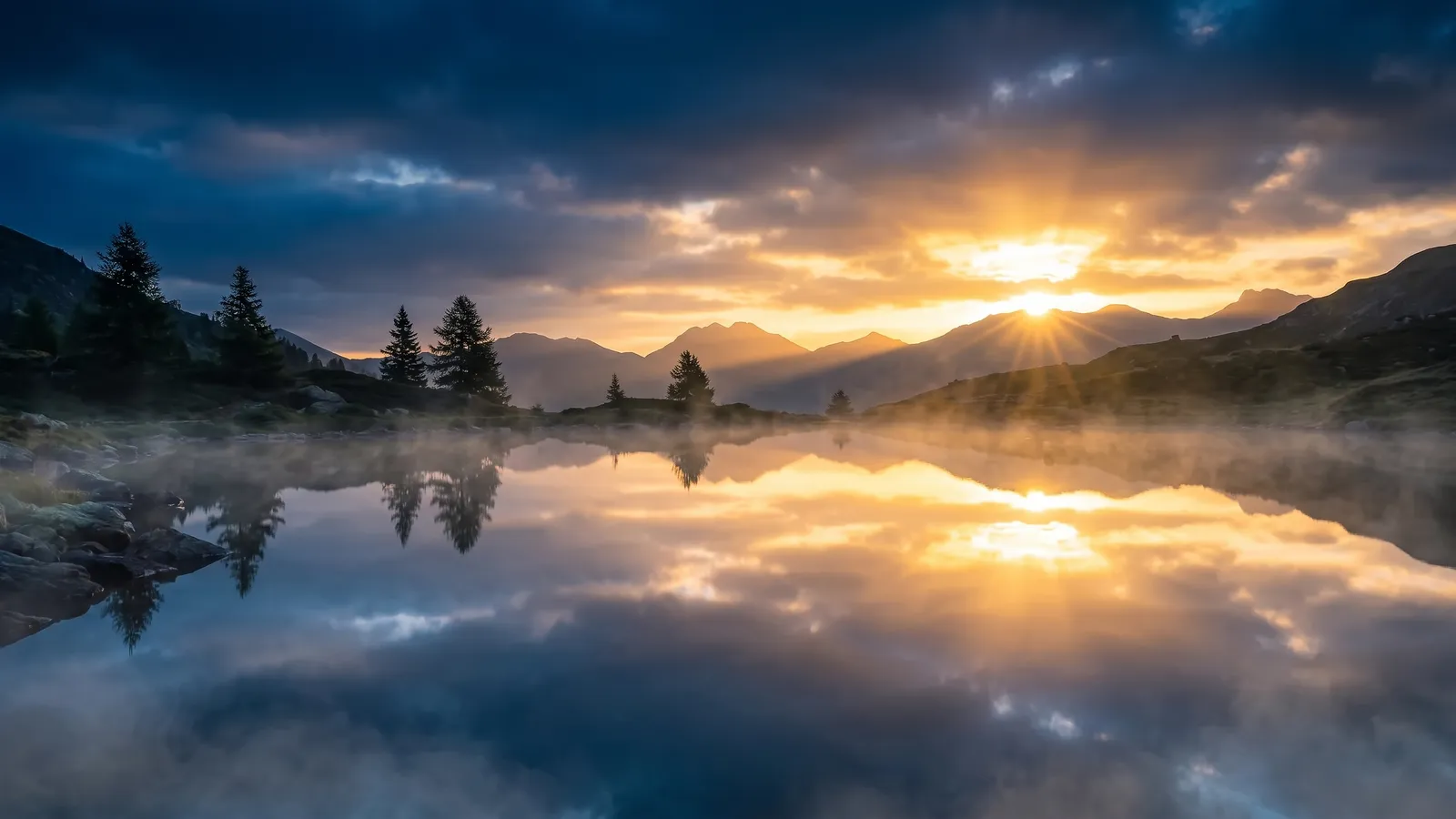 A still mountain lake at sunrise mirroring the peaks, pines and sky line for line
